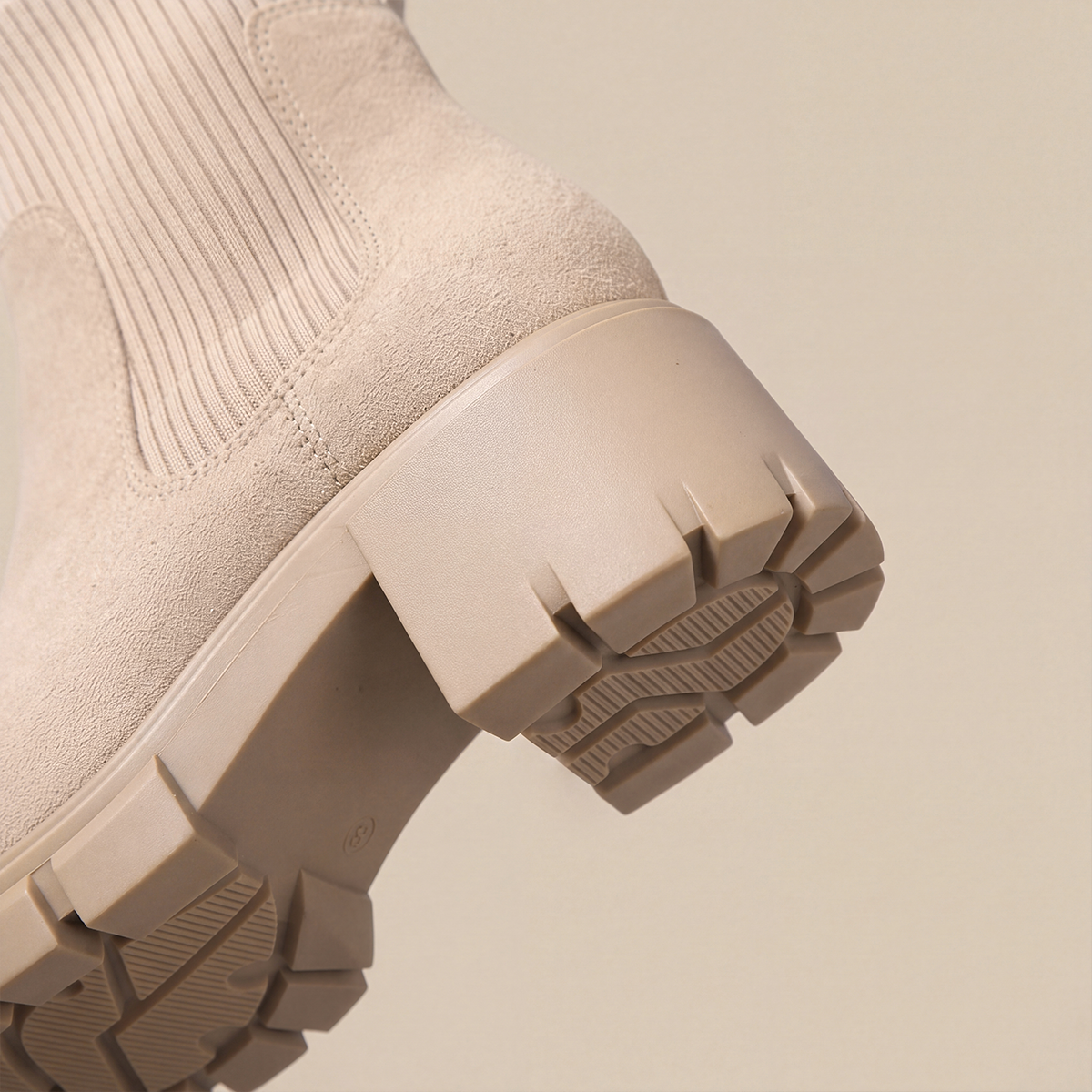 Close-up of the deep tread pattern on the outsole of khaki Chelsea boots