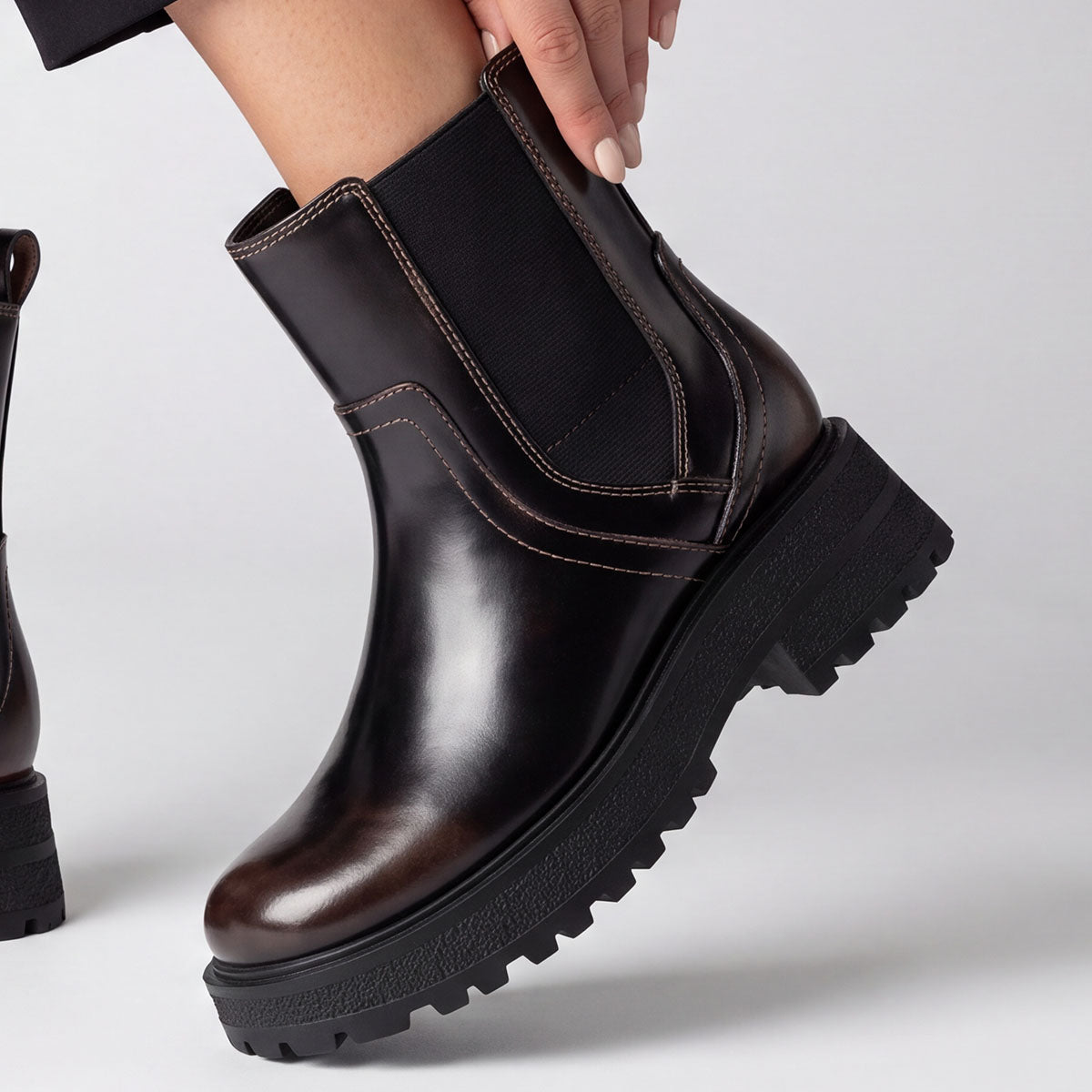 Close-up of the elastic side panel being stretched on a black chunky Chelsea boot