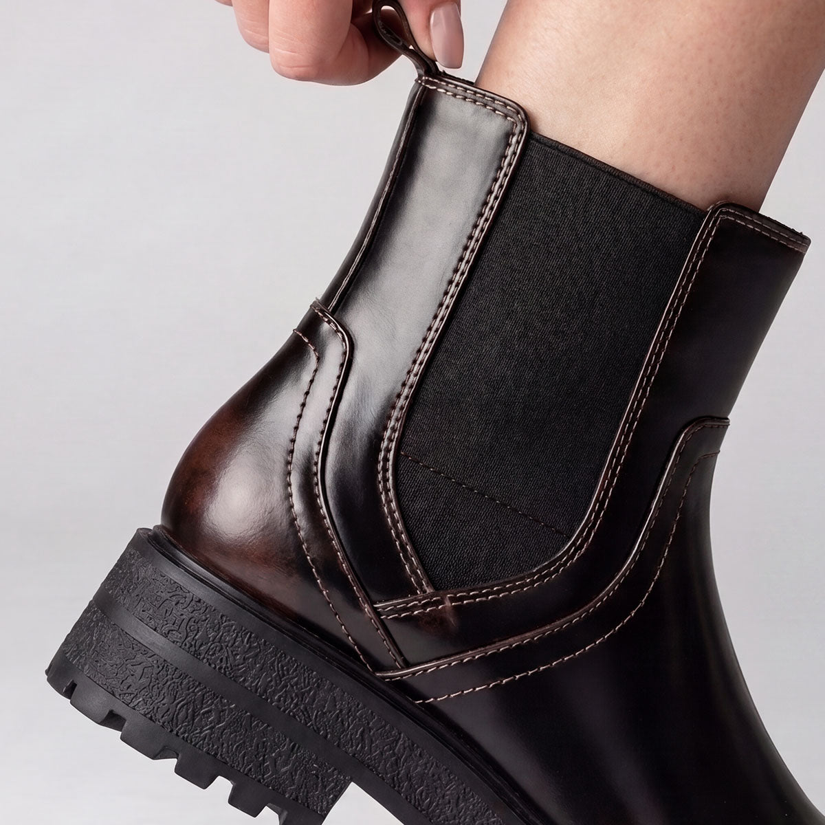 Close-up of the rear pull tab being used to pull on a black Chelsea boot