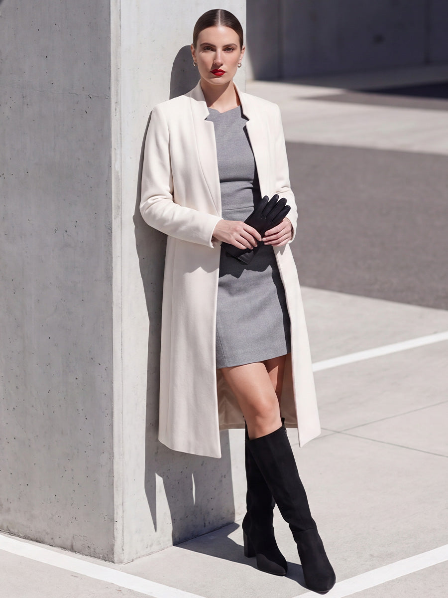 Model wearing black suede knee-high boots with a cream coat and gray mini dress