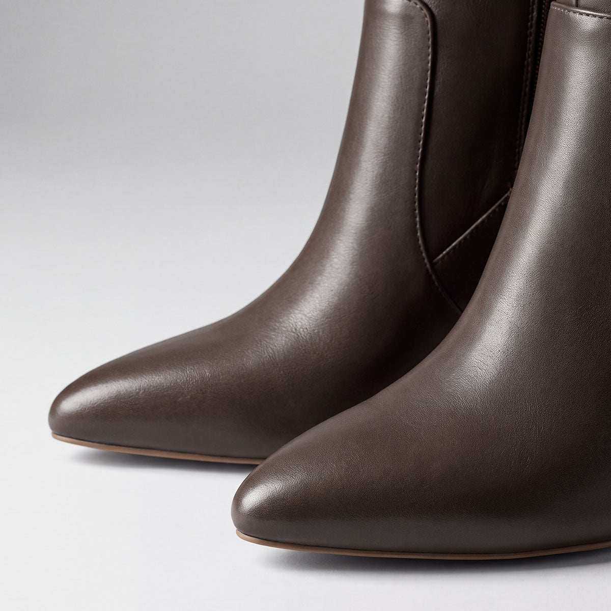 Close-up of the pointed toes and smooth uppers on chocolate knee-high boots