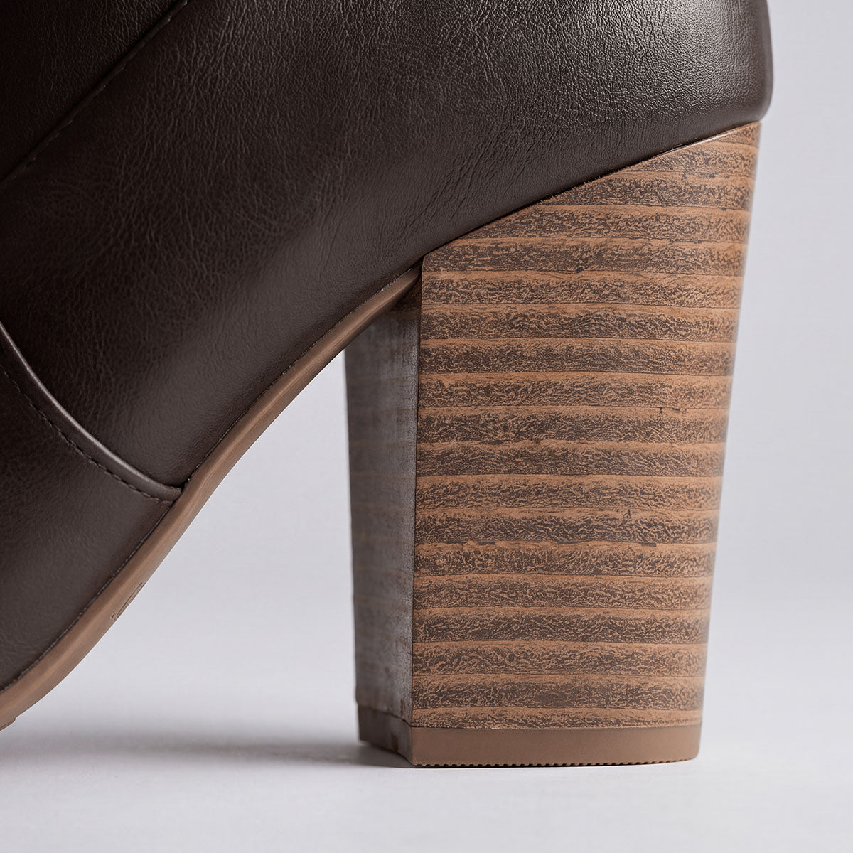 Close-up of the wood-look block heel on a chocolate knee-high boot