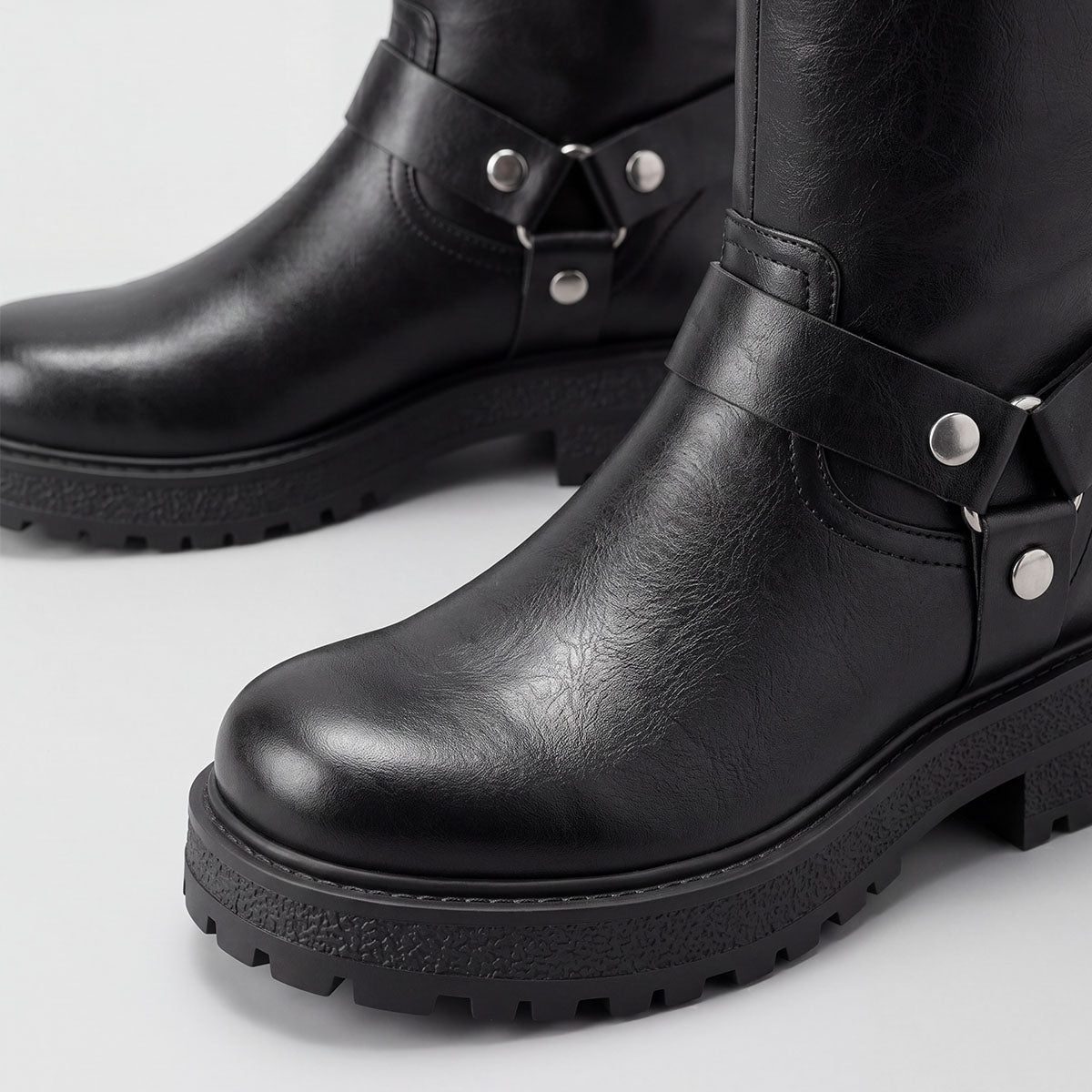 Close-up of the rounded toes and chunky lug soles on black moto boots