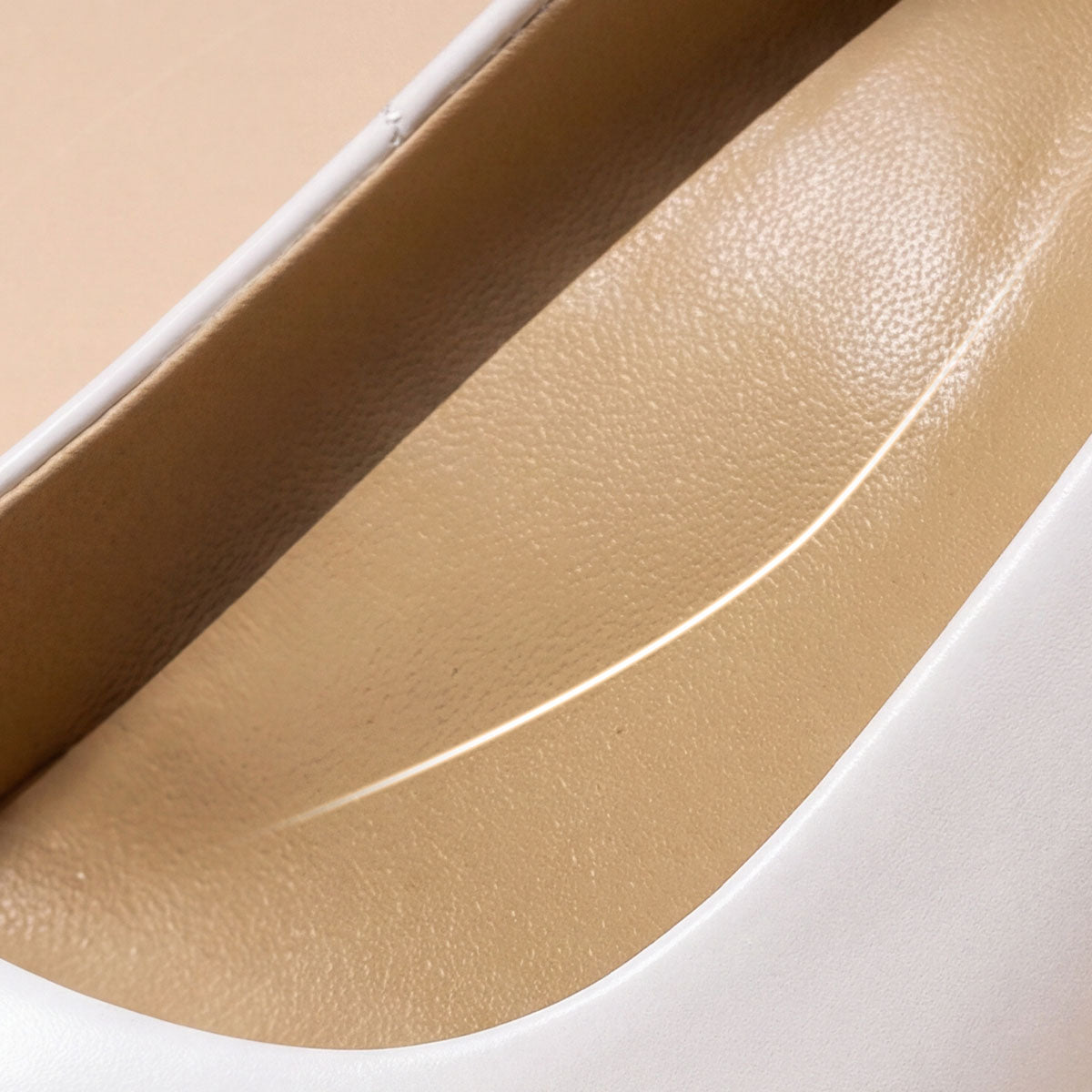 Close-up of the contoured cushioned footbed inside a white pointed-toe pump