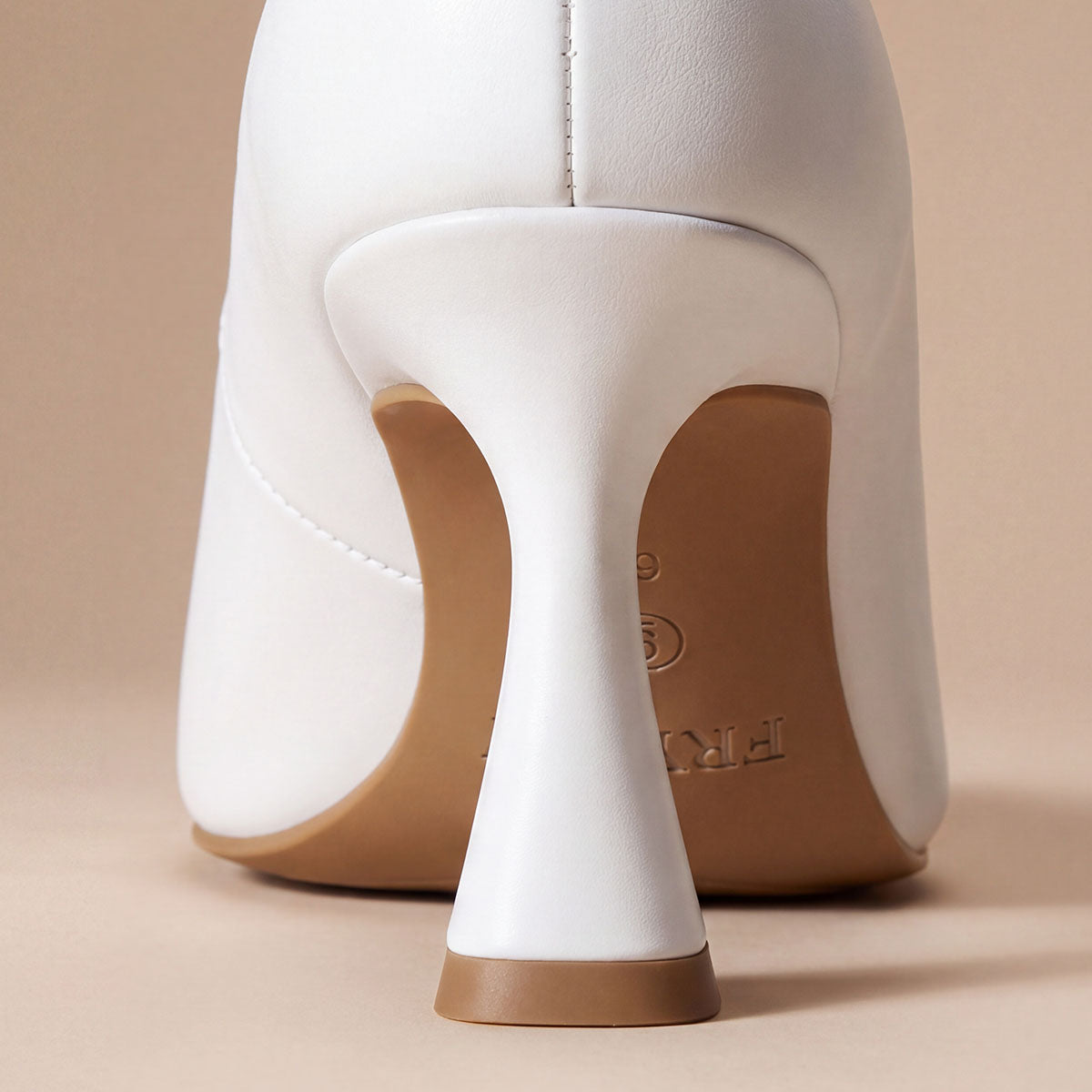 Rear view of the flared heel and heel tip on a white pointed-toe pump