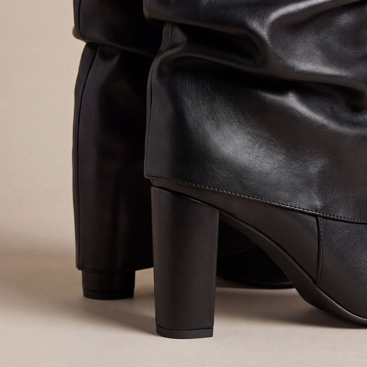 Rear close-up of black slouchy boots showing the low heels and overlapping shaft panels