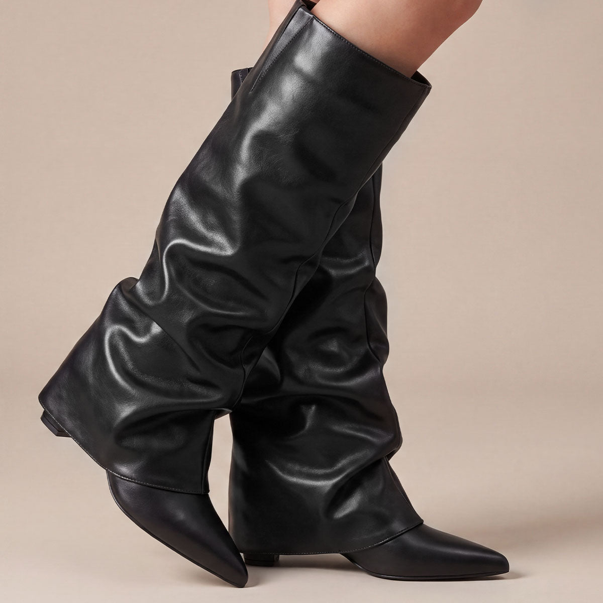 Close-up of black pointed-toe boots showing the soft folds along the slouchy shafts