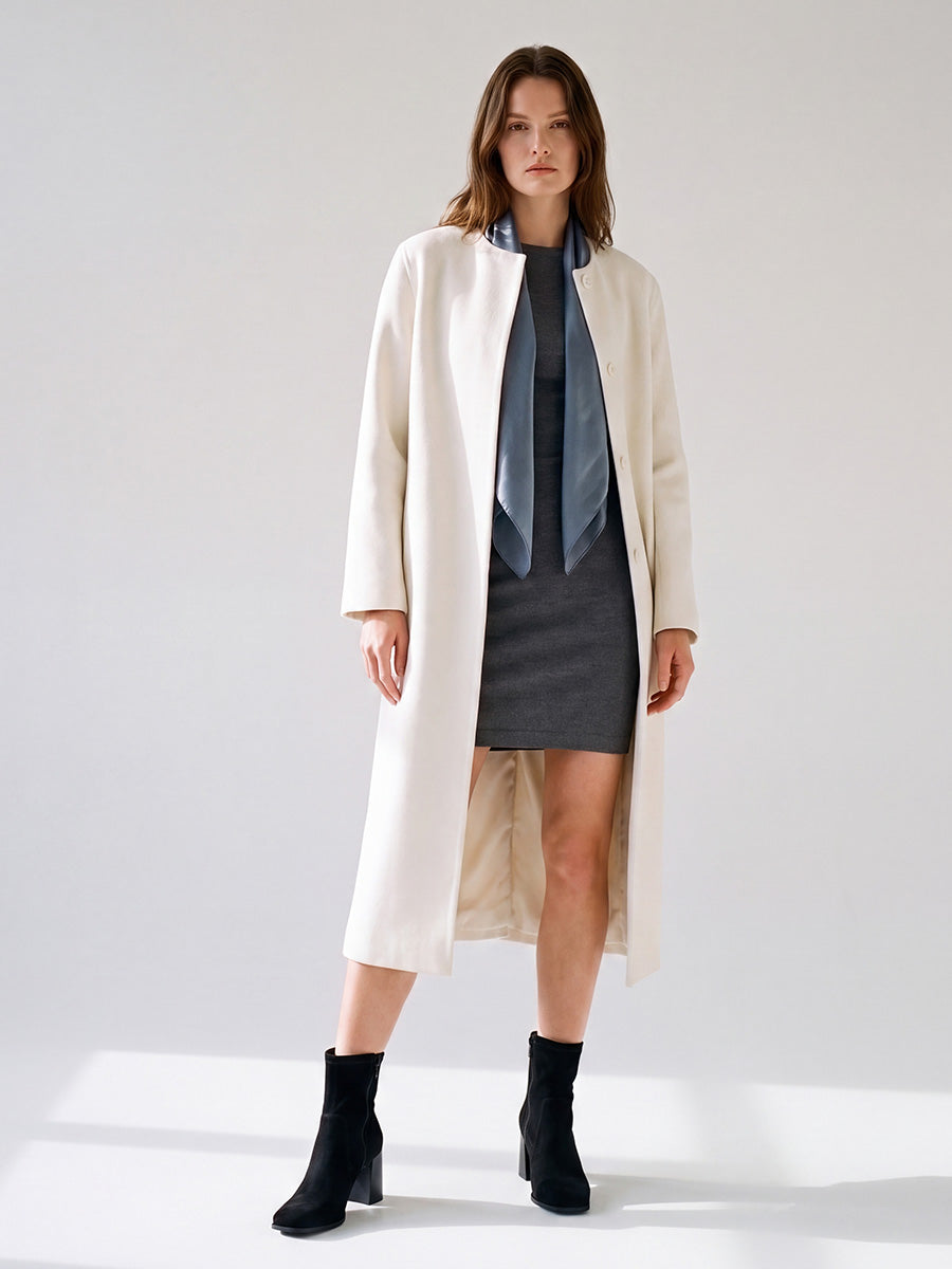 Model wearing black suede square-toe ankle boots with a cream coat and gray mini skirt