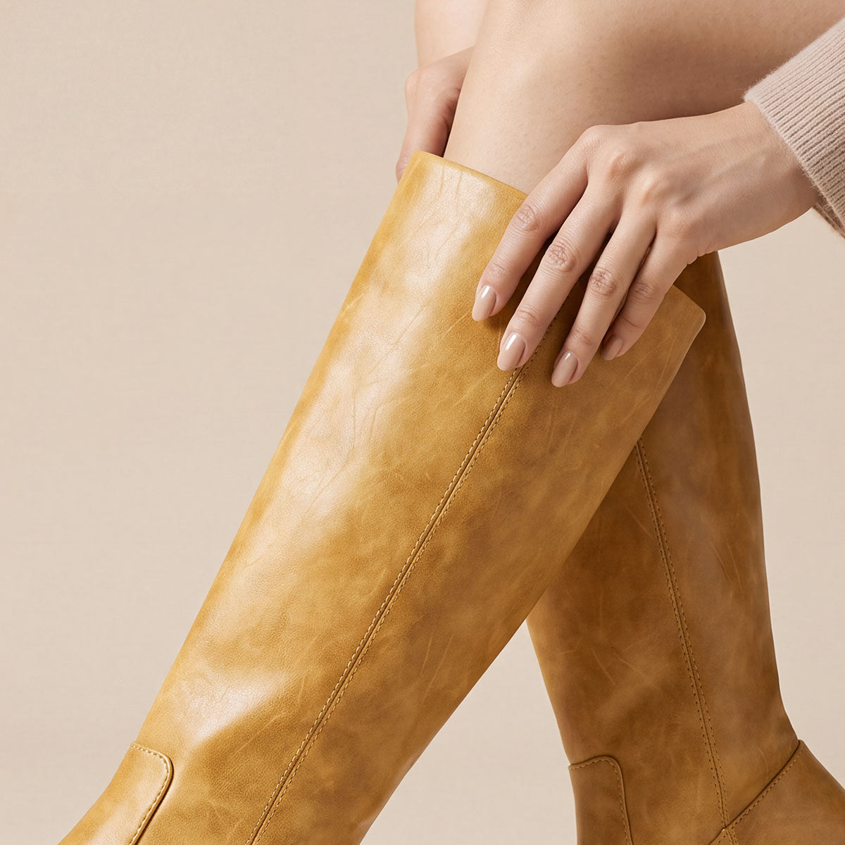 Close-up of the mottled finish and stitched seam on a yellow knee-high boot shaft
