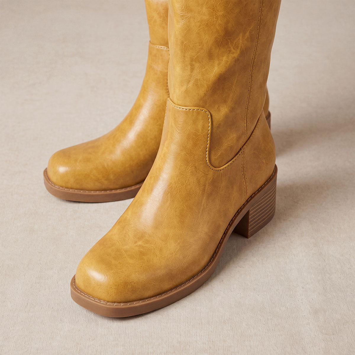 Close-up of the softly squared toes and mottled yellow uppers on knee-high boots